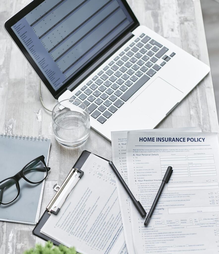 A Laptop and Insurance Policy on the Table